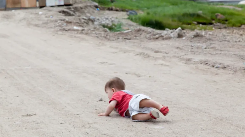 砂利道で転ぶ、赤い服を着た小さな男の子