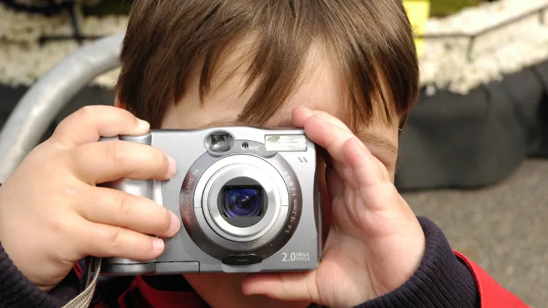 カメラを構えて写真を撮ろうとしている小さな男の子