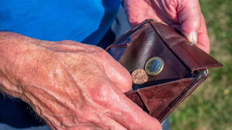 少ない小銭しか入っていない、年配の男性が持つ茶色の財布