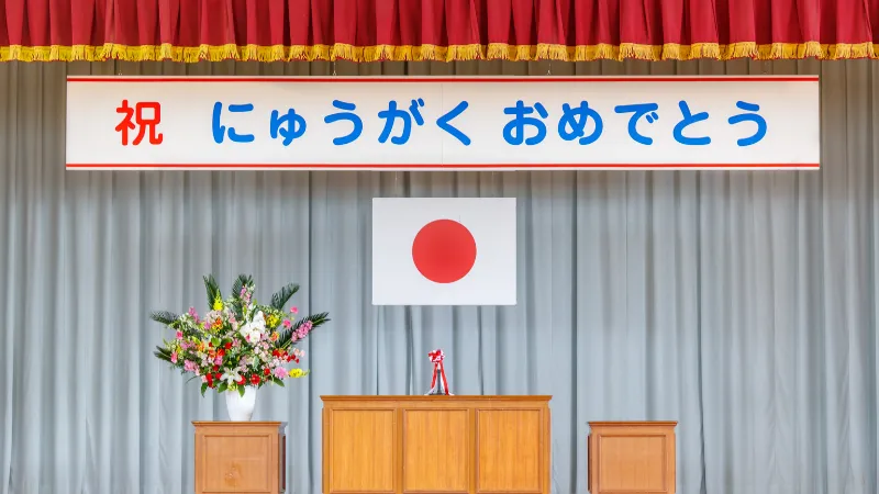 入学式会場のステージ上に飾られたフラワーアレンジメントと日本国旗
