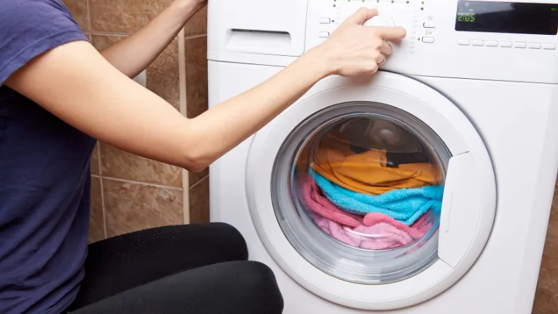 洗濯をするため洗濯機のスイッチを入れている女性