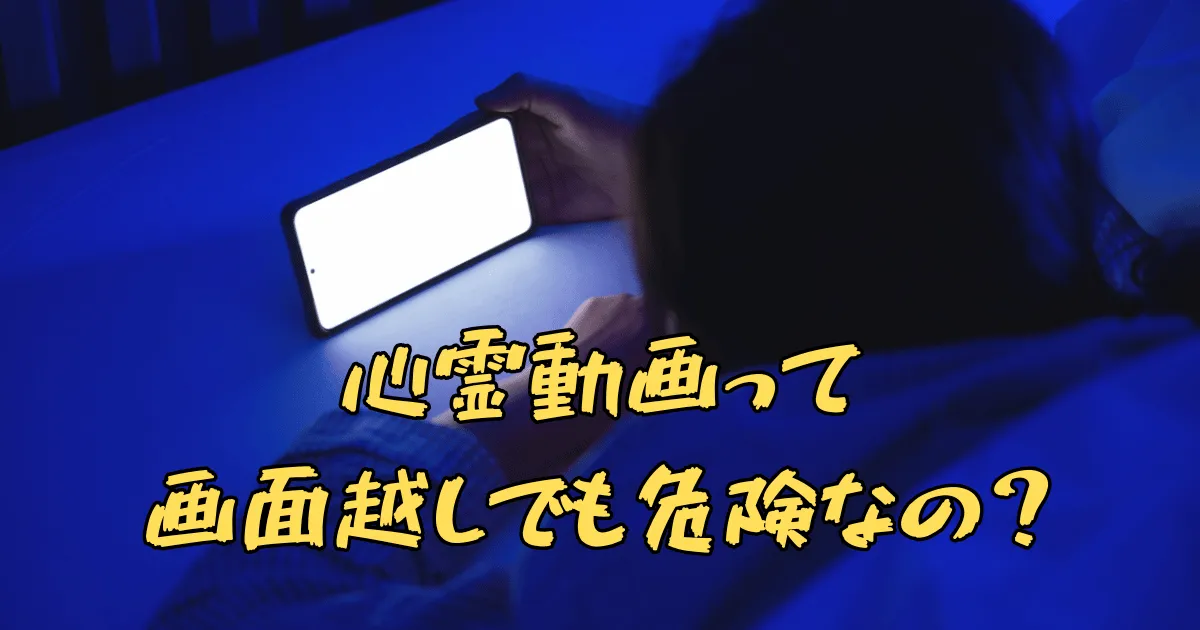 暗い寝室で布団に入りながらスマホを見ている女性